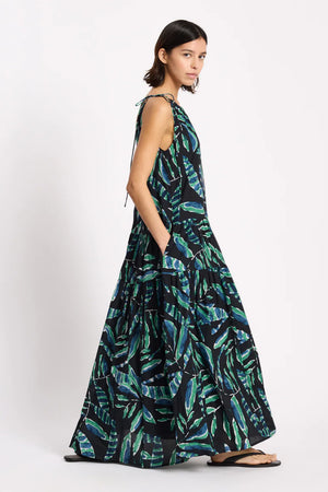 Woman wearing a long, sleeveless dress with a leaf pattern on a white background