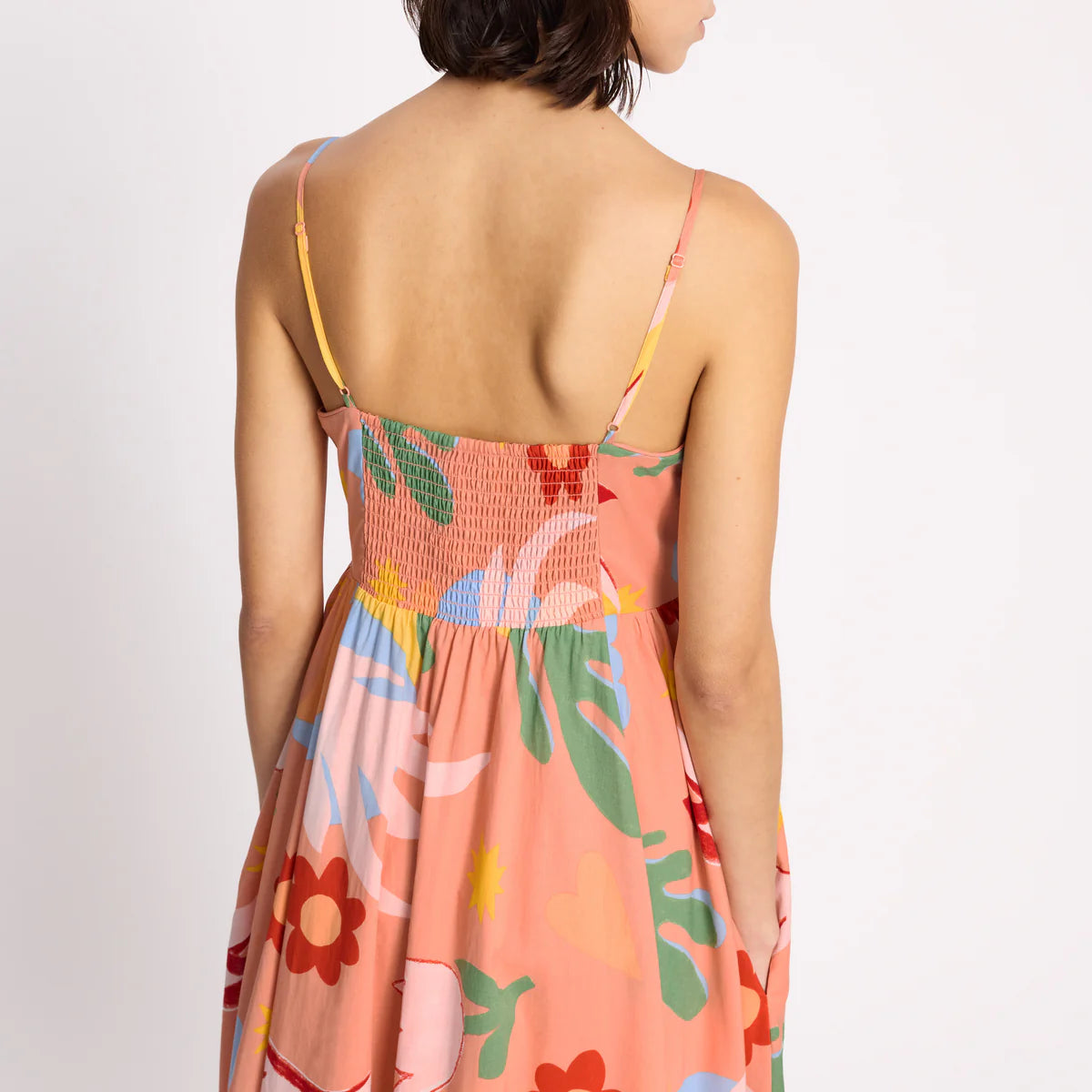 Woman wearing a colorful floral dress with a plain background