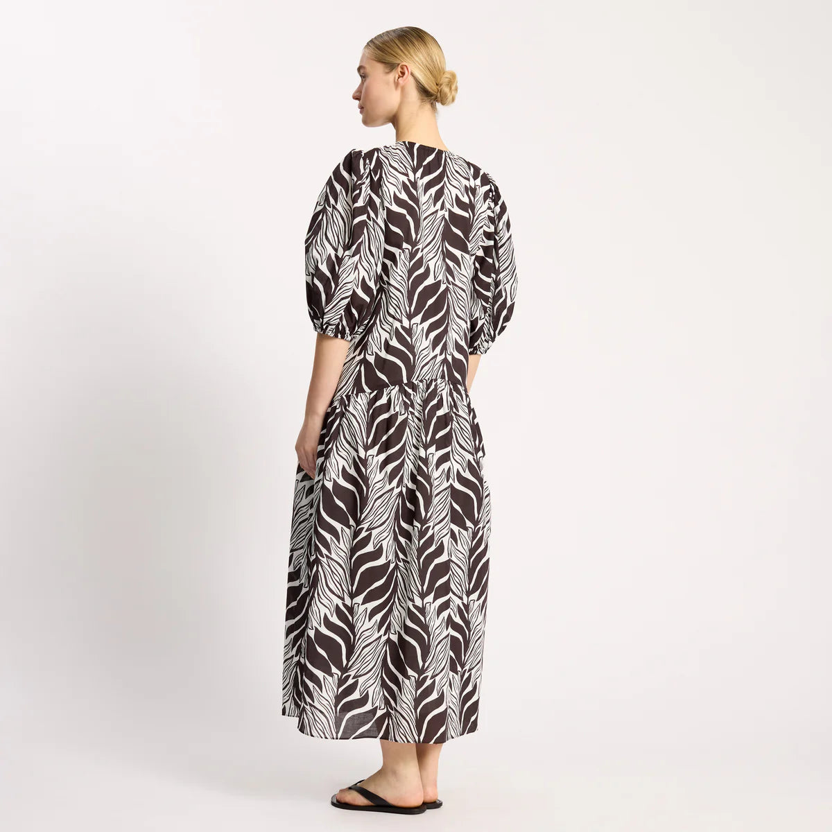 Woman wearing a black and white patterned dress on a white background