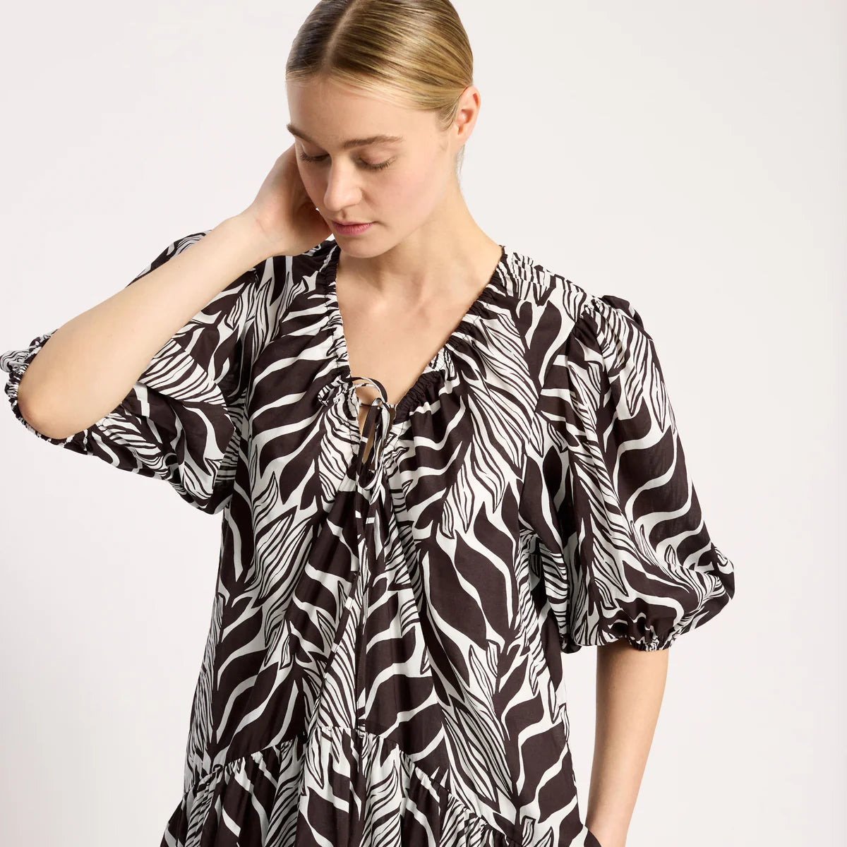 Woman wearing a black and white patterned blouse on a white background