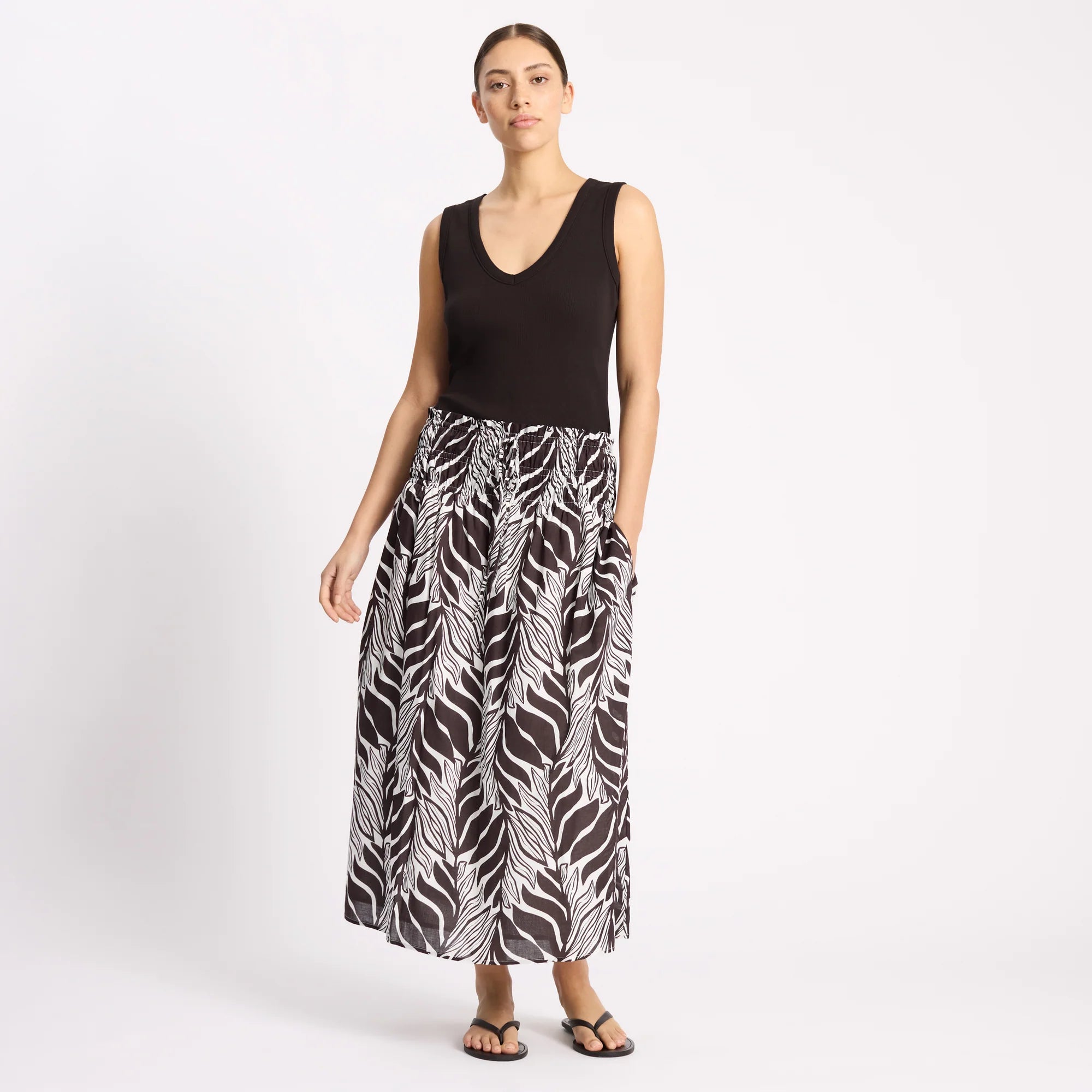 Woman wearing a black sleeveless top and zebra print skirt on a white background