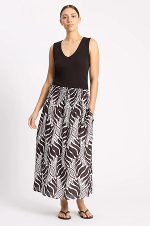 Woman wearing a black sleeveless top and zebra print skirt on a white background