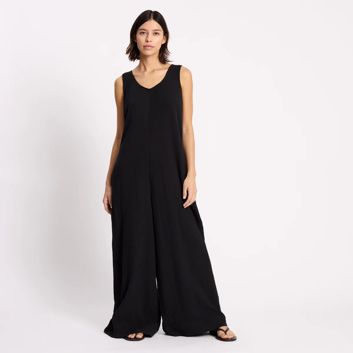Woman wearing a black sleeveless jumpsuit on a white background