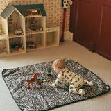 Thoren Eco Playmat in Leopard laid on a bedroom carpet with a baby crawling towards wooden toys