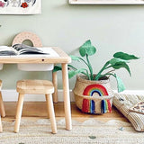 Vivid Rainbow Belly Basket holding a green plant, next to a wooden children's table and stool
