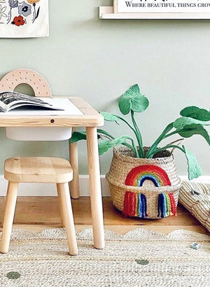 Vivid Rainbow Belly Basket holding a green plant, next to a wooden children's table and stool