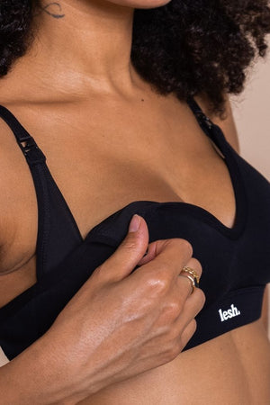 Person wearing a black bra with 'lesh' branding on a beige background