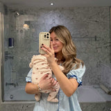 Woman holding a baby in a bathroom taking a mirror selfie.