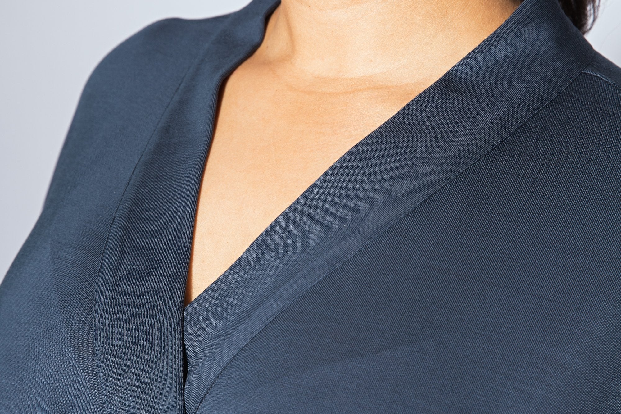 Navy blue top worn by a person against a light gray background