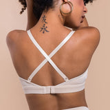 Woman wearing a beige bralette with criss-cross straps on a beige background