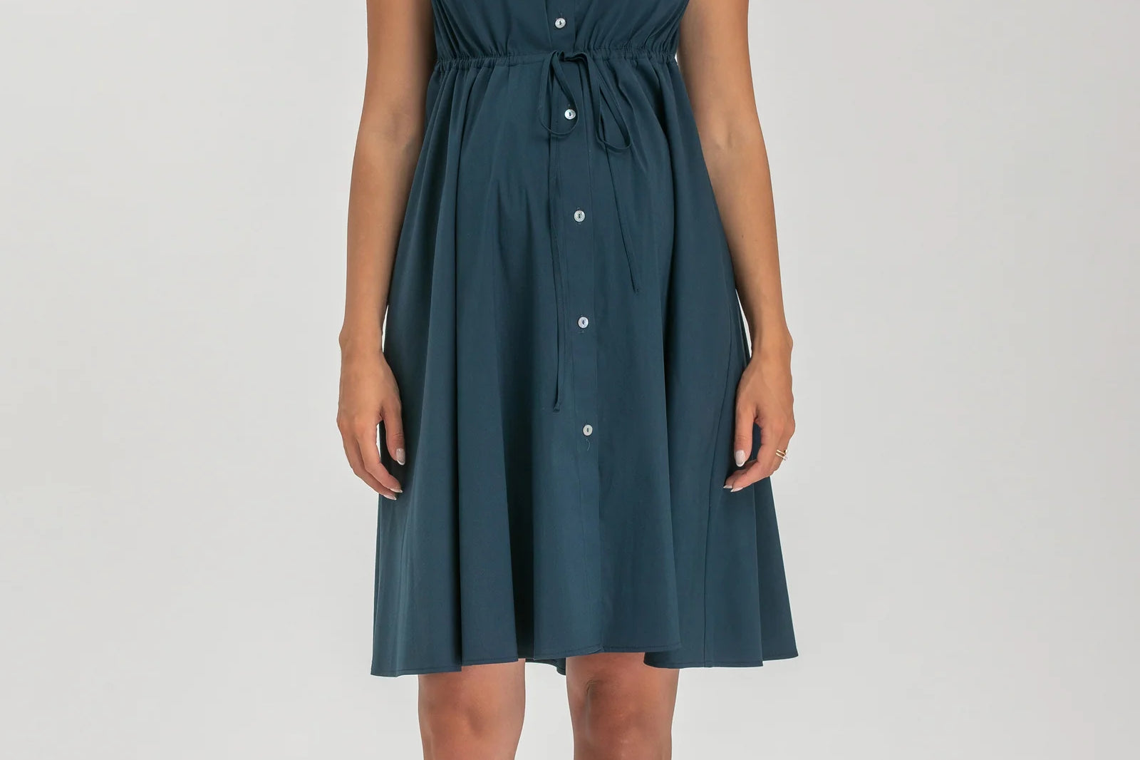Woman wearing a teal dress with a belt on a white background