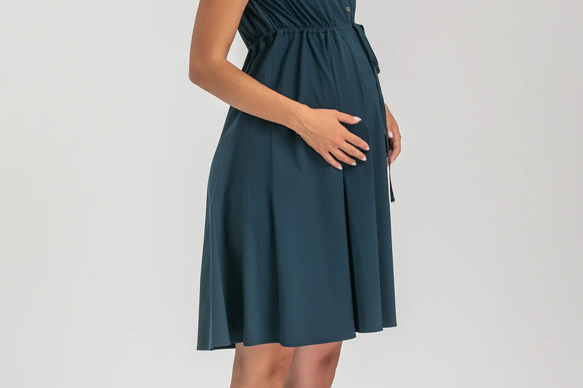 Pregnant woman wearing navy blue shirt dress on grey background