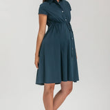 Pregnant woman wearing navy blue shirt dress on grey background
