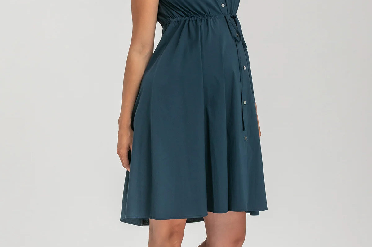 Pregnant woman wearing navy blue shirt dress on grey background