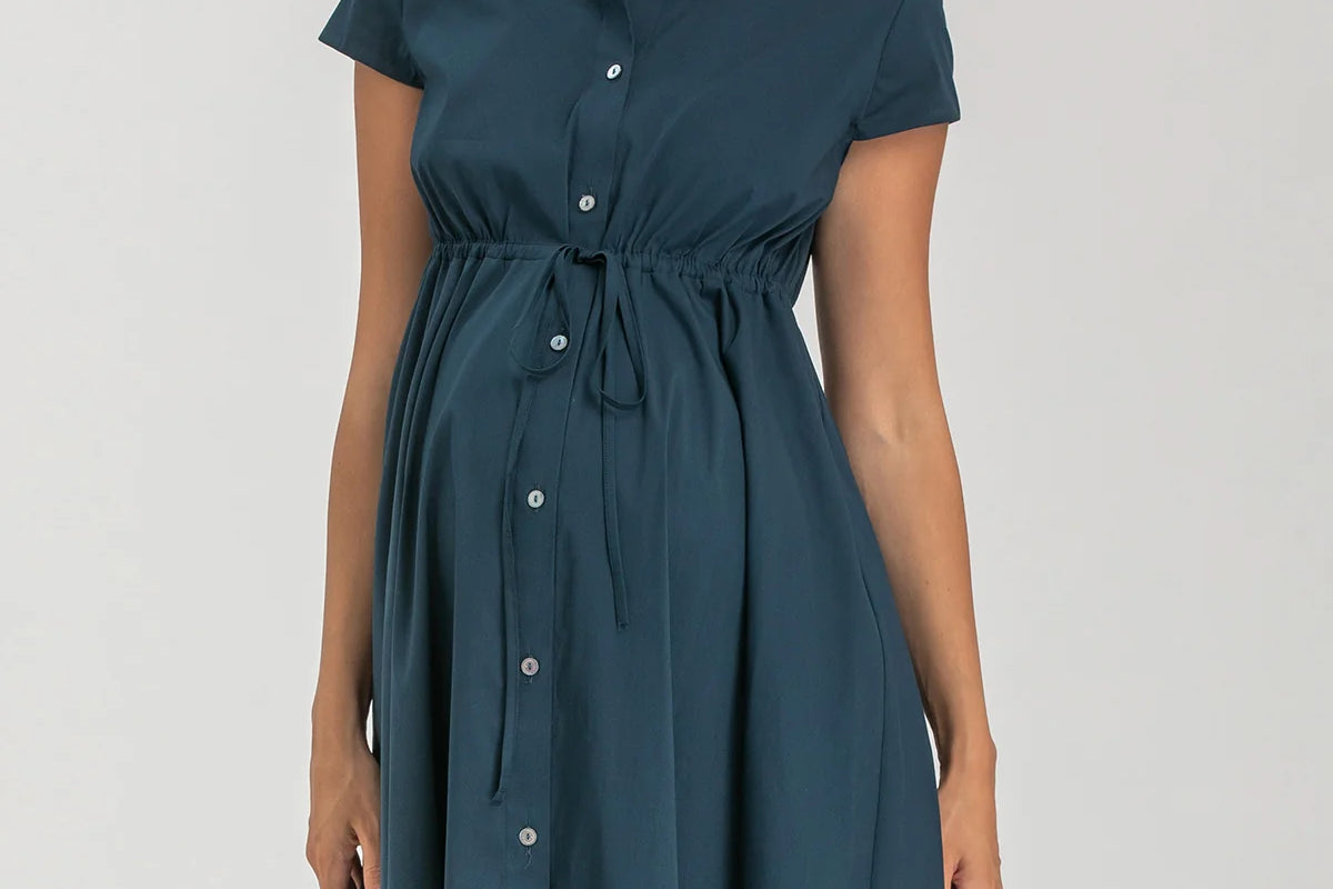 Pregnant woman wearing navy blue shirt dress on grey background