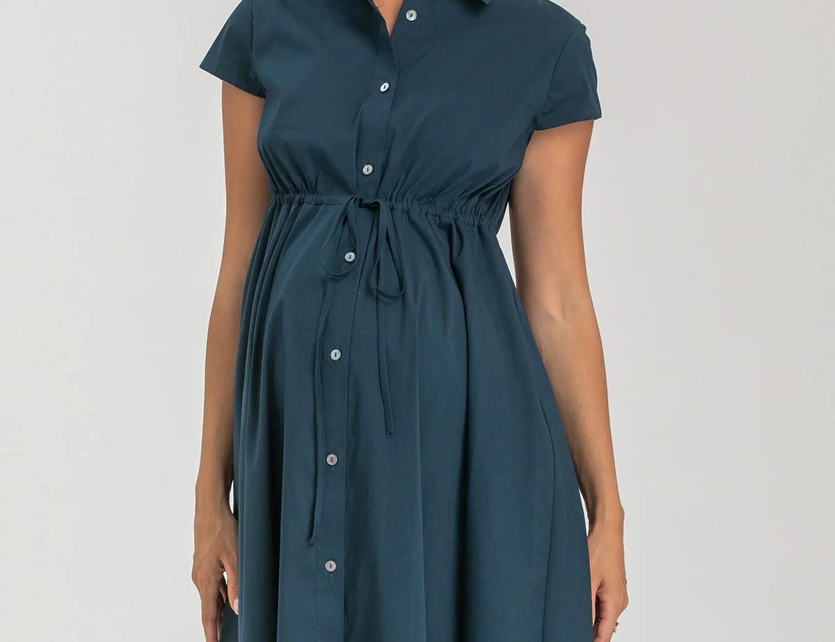 Pregnant woman wearing navy blue shirt dress on grey background