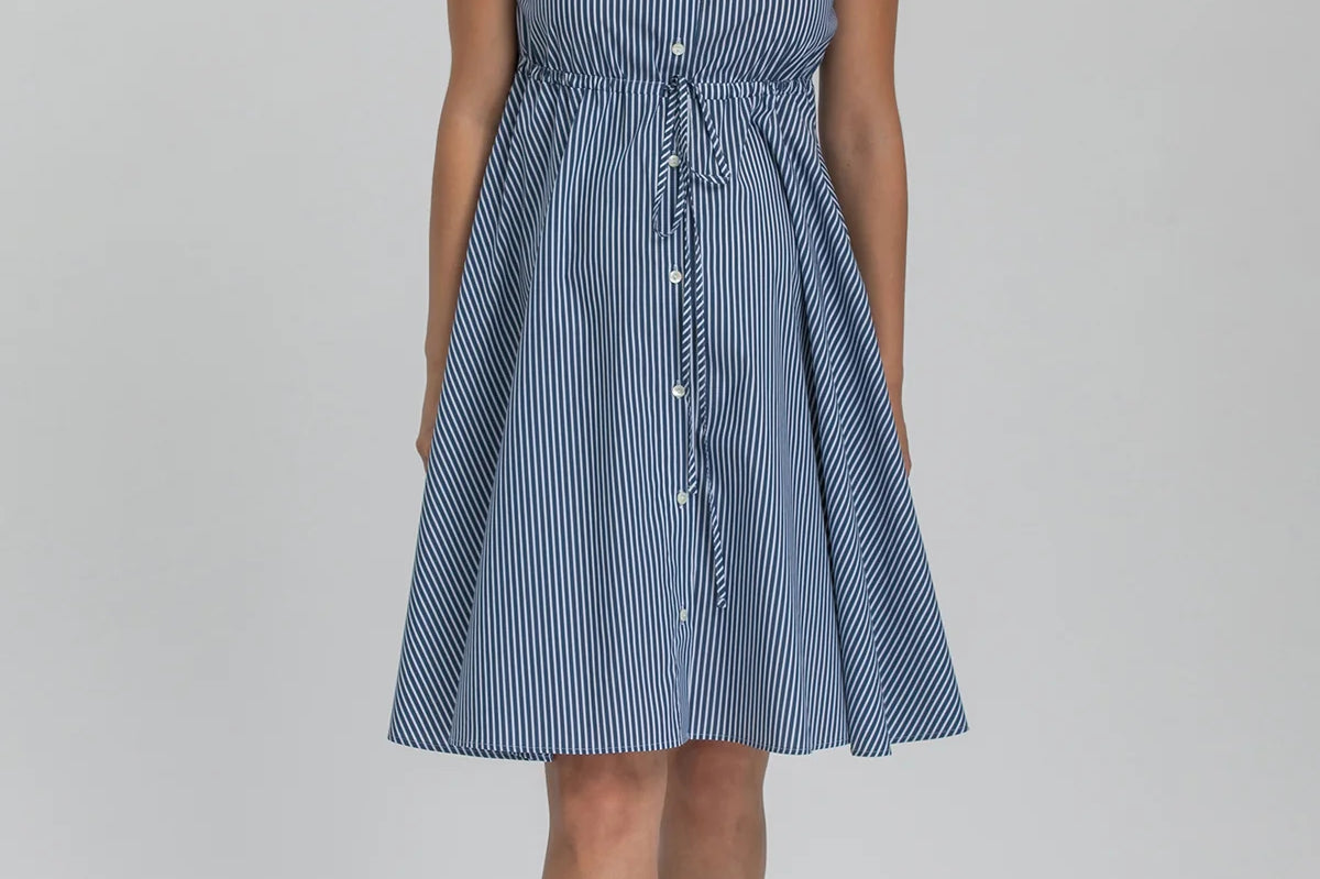 Woman wearing a blue striped dress on a gray background