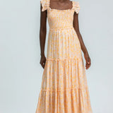 Woman wearing a yellow tiered dress on a light gray background