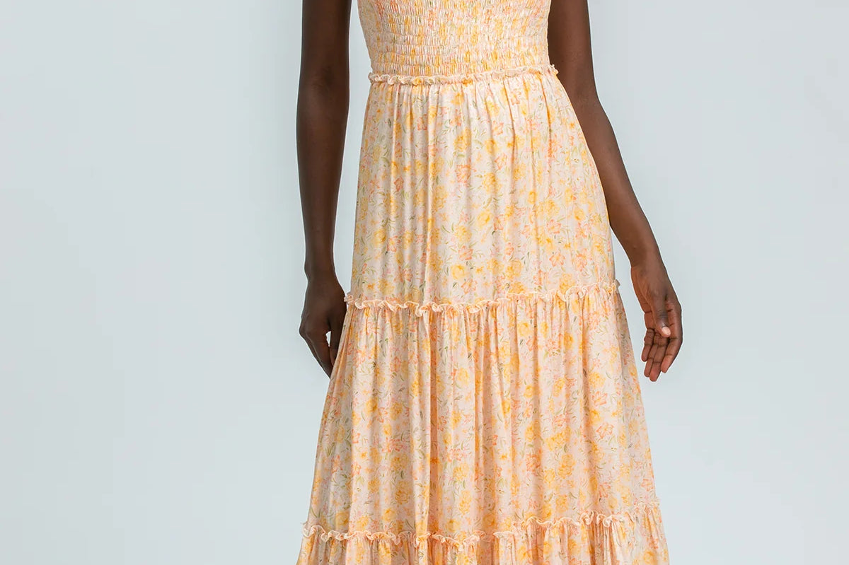 Woman wearing a yellow tiered dress on a light gray background