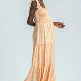 Woman wearing a yellow tiered dress on a light gray background
