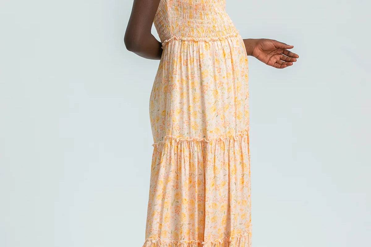 Woman wearing a yellow tiered dress on a light gray background