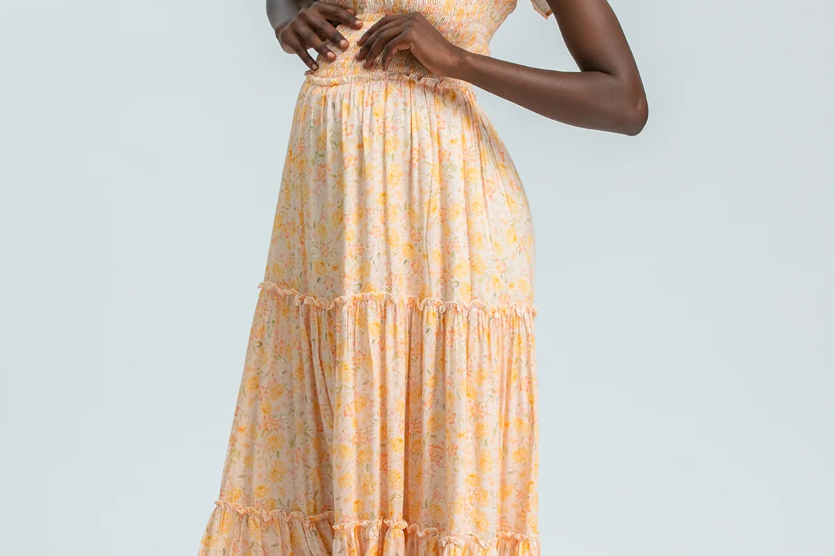 Woman wearing a yellow checkered dress with ruffled sleeves on a light gray background