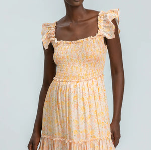 Woman wearing a yellow floral dress against a light gray background
