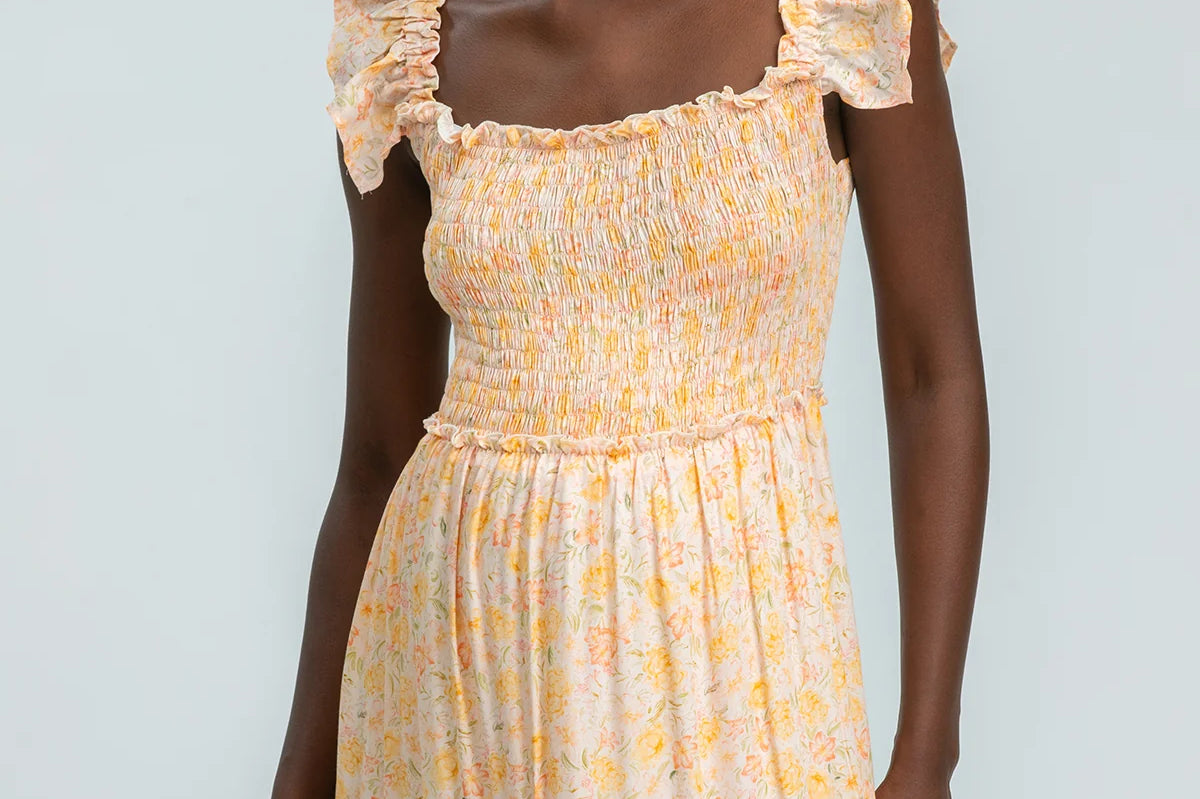 Woman wearing a yellow floral dress against a light gray background