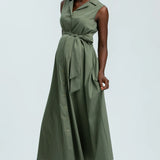 Woman wearing green sleeveless full length shirt dress on pale background