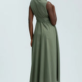 Woman wearing green sleeveless full length shirt dress on pale background