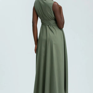 Woman wearing green sleeveless full length shirt dress on pale background