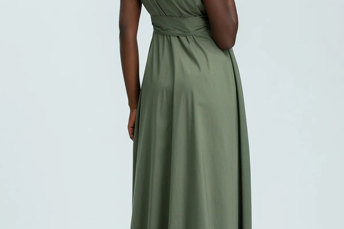Woman wearing green sleeveless full length shirt dress on pale background