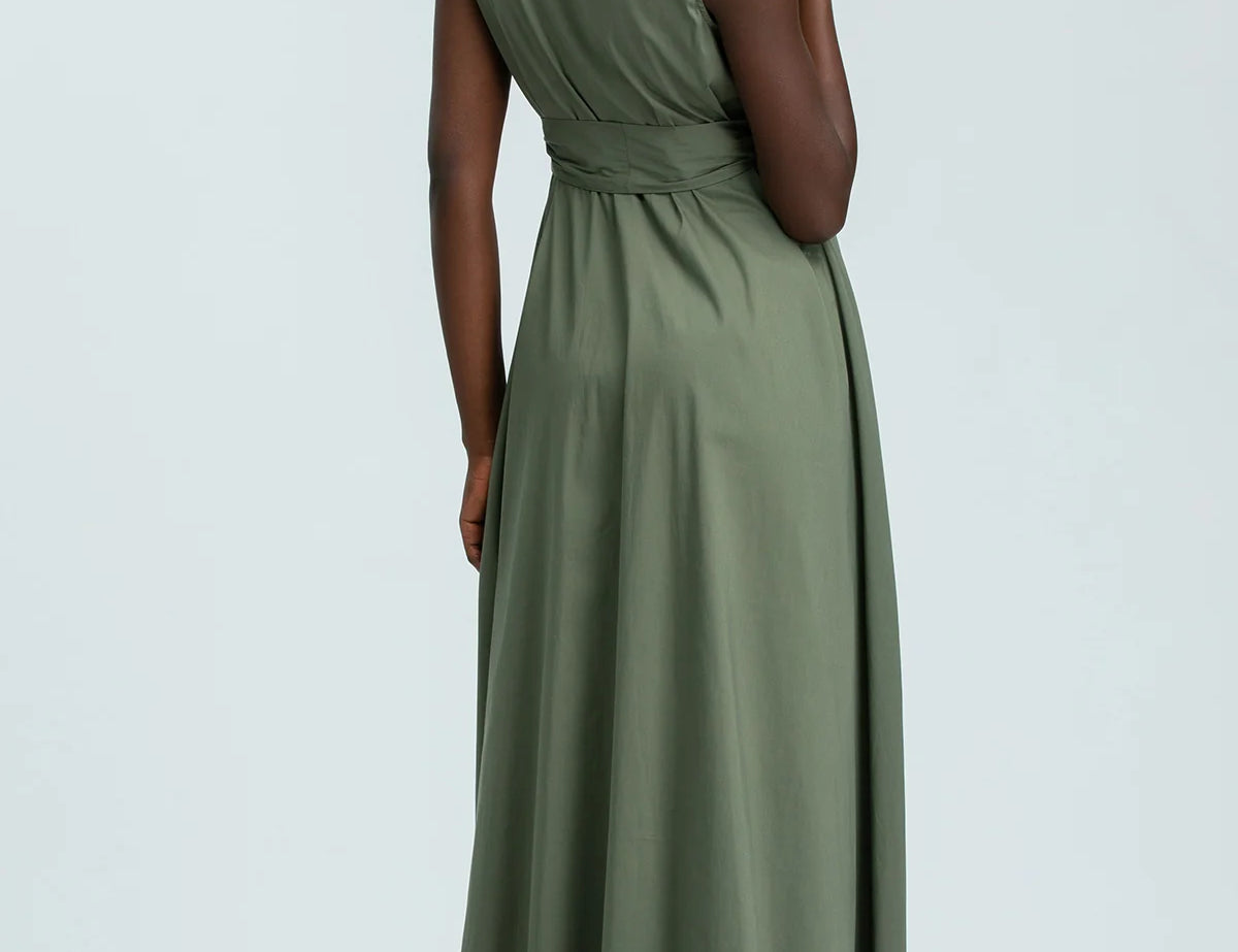 Woman wearing green sleeveless full length shirt dress on pale background