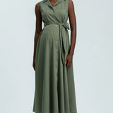 Woman wearing green sleeveless full length shirt dress on pale background