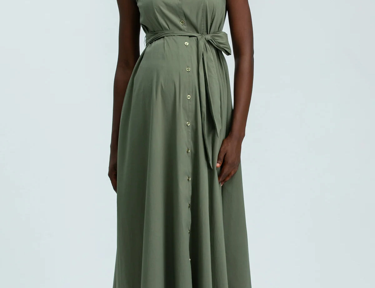 Woman wearing green sleeveless full length shirt dress on pale background