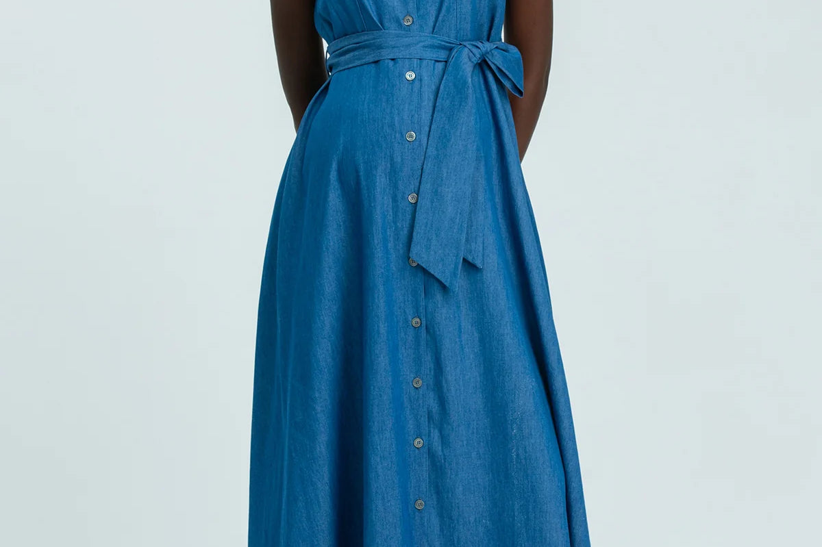 Woman wearing a blue sleeveless dress on a light gray background