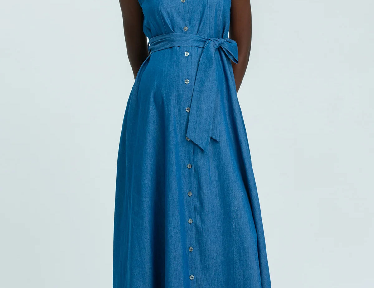 Woman wearing a blue sleeveless dress on a light gray background