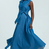 Woman wearing a blue sleeveless dress with buttons on a white background