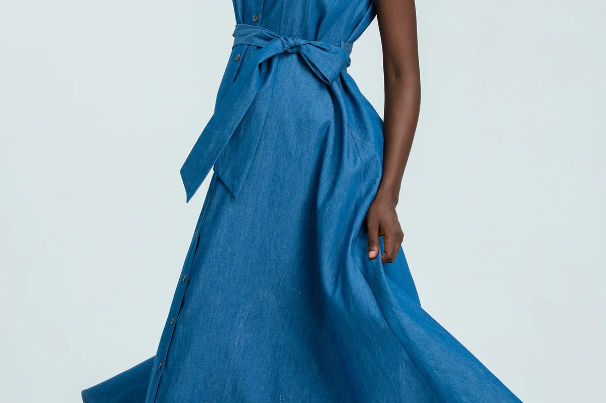 Woman wearing a blue sleeveless dress with buttons on a white background