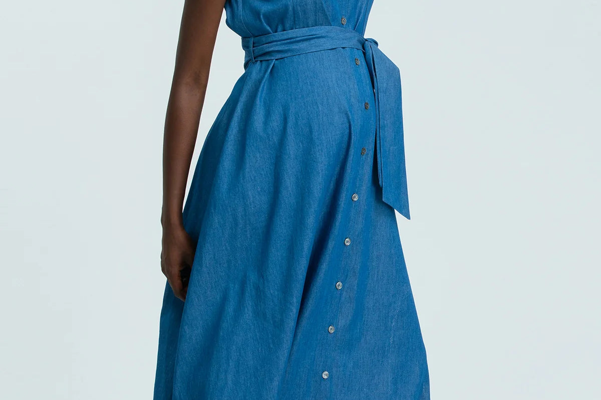 Woman wearing a blue sleeveless dress with buttons on a white background