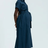 Woman wearing a teal dress with a belt on a white background