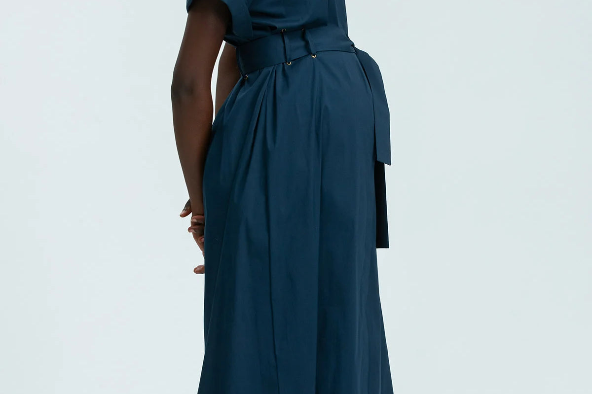 Woman wearing a teal dress with a belt on a white background