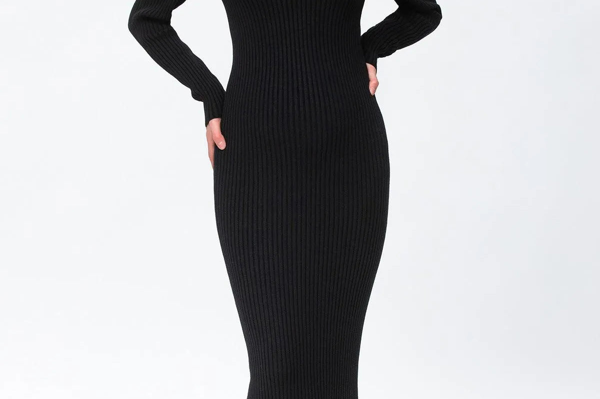 A woman modeling a black ribbed long-sleeve V-neck midi dress with taupe ankle boots against a plain white studio background.