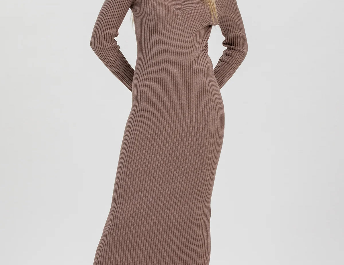 A woman modeling a ribbed knit long-sleeve midi dress in taupe brown, paired with dark brown patent leather ankle boots, against a light gray studio background.