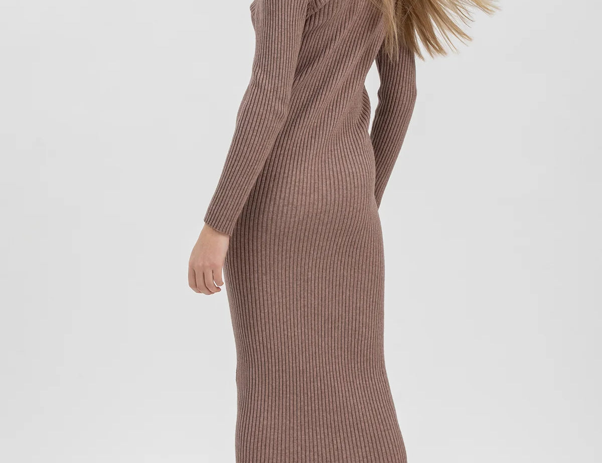 A woman modeling a ribbed knit long-sleeve midi dress in a muted taupe-brown color, paired with dark brown lace-up ankle boots, against a plain light gray studio background.