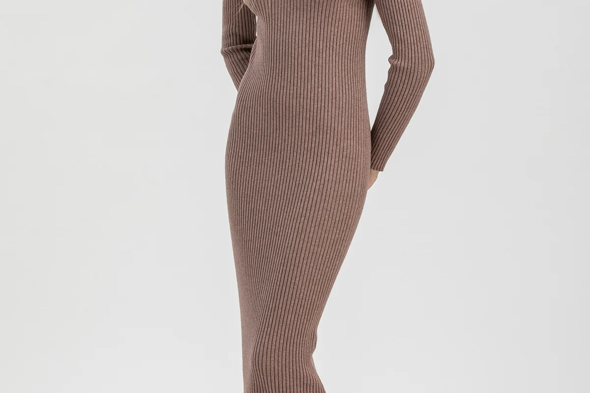 A woman modeling a ribbed long-sleeve midi dress in a taupe-brown color, paired with dark brown ankle boots, against a plain light gray studio background.