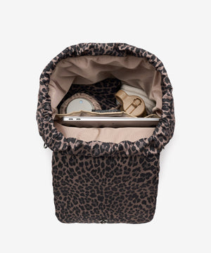Leopard print baby bouncer with items inside on a white background