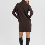 A woman shown from the back wearing a dark brown long-sleeve knit dress with a mock neck and black knee-high heeled boots, photographed against a light gray studio background.