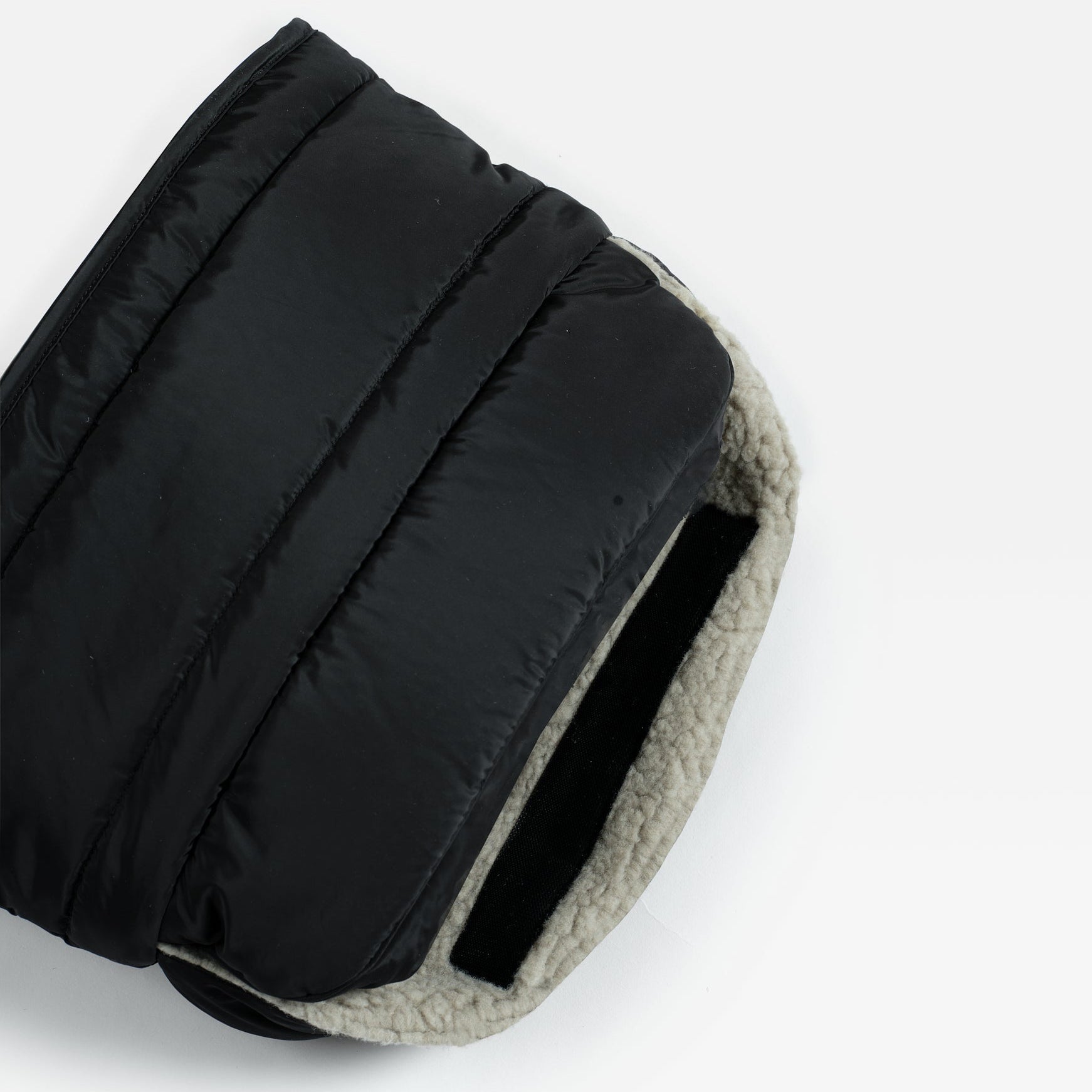 Agnar Eco stroller mitten in black, close-up of the open end showing the light fleece lining and a black fastening strip