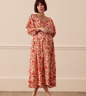 Albaray cream midi dress with orange botanical print, made from 100% organic cotton. Features a gathered tie neckline, ¾ sleeves, elasticated waist, and lined skirt with pockets – ideal for everyday comfort and effortless style.